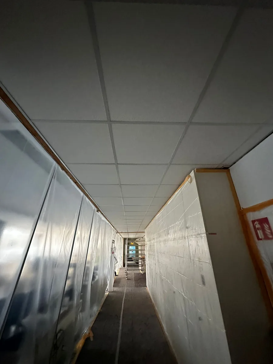 B&uuml;rogang mit neu eingebauter Rasterdecke, die W&auml;nde sind mit Folie gesch&uuml;tzt