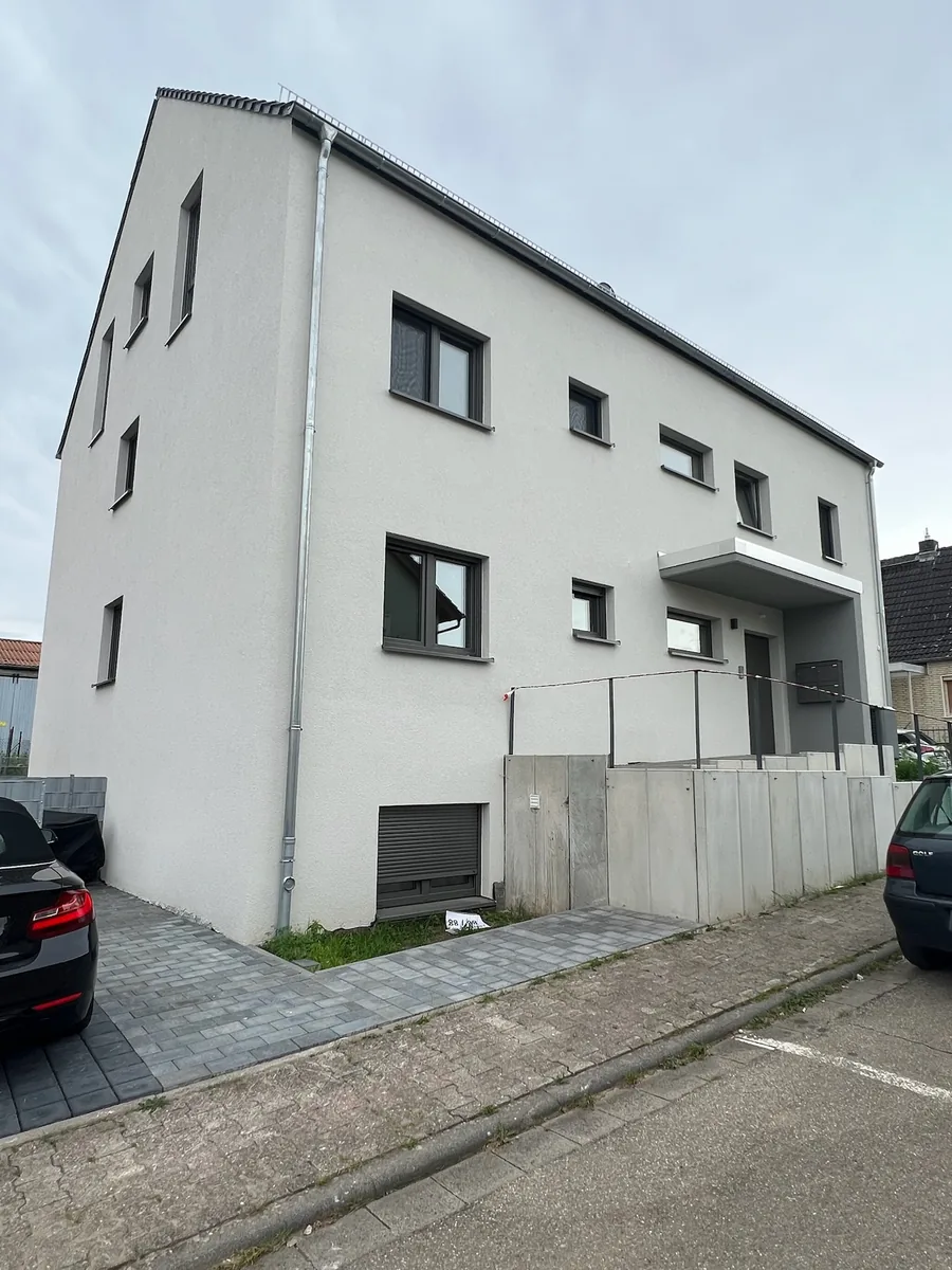 Fertiggestelltes Mehrfamilienhaus mit anthrazitfarbenen Fenstern, T&uuml;ren und Rolll&auml;den