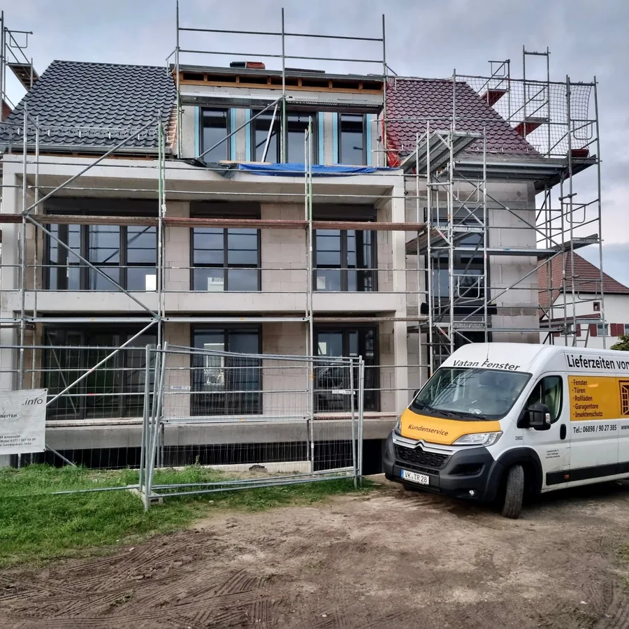 Neubau im Rohbau mit Ger&uuml;st und bereits eingesetzten Fensterelementen, davor ein Servicefahrzeug